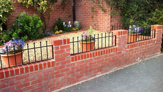 metal railings on a small brick wall with plant pots